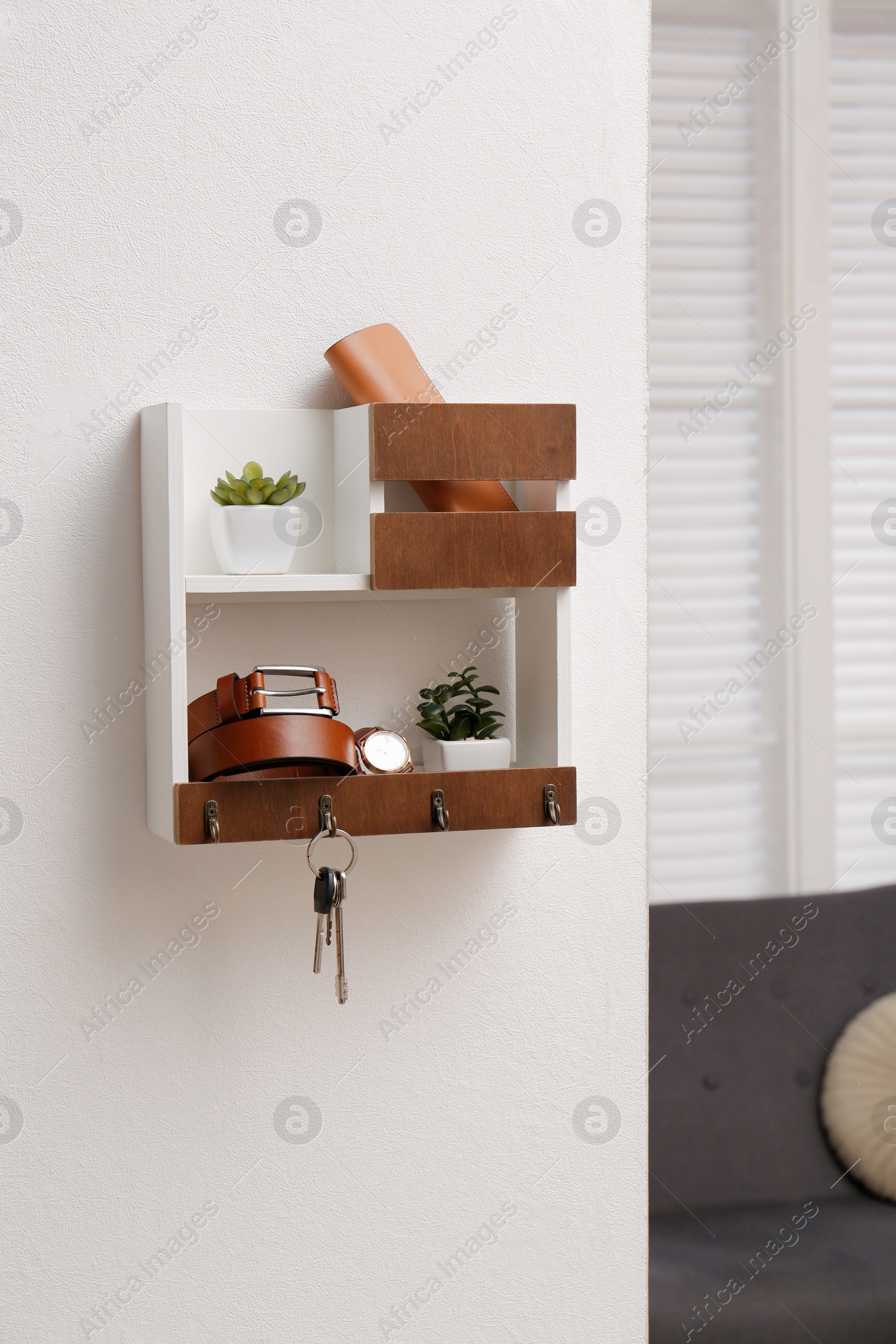 Photo of Hallway interior with stylish accessories and wooden hanger for keys on white wall