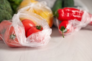 Photo of Plastic bags with fresh products on white table, closeup