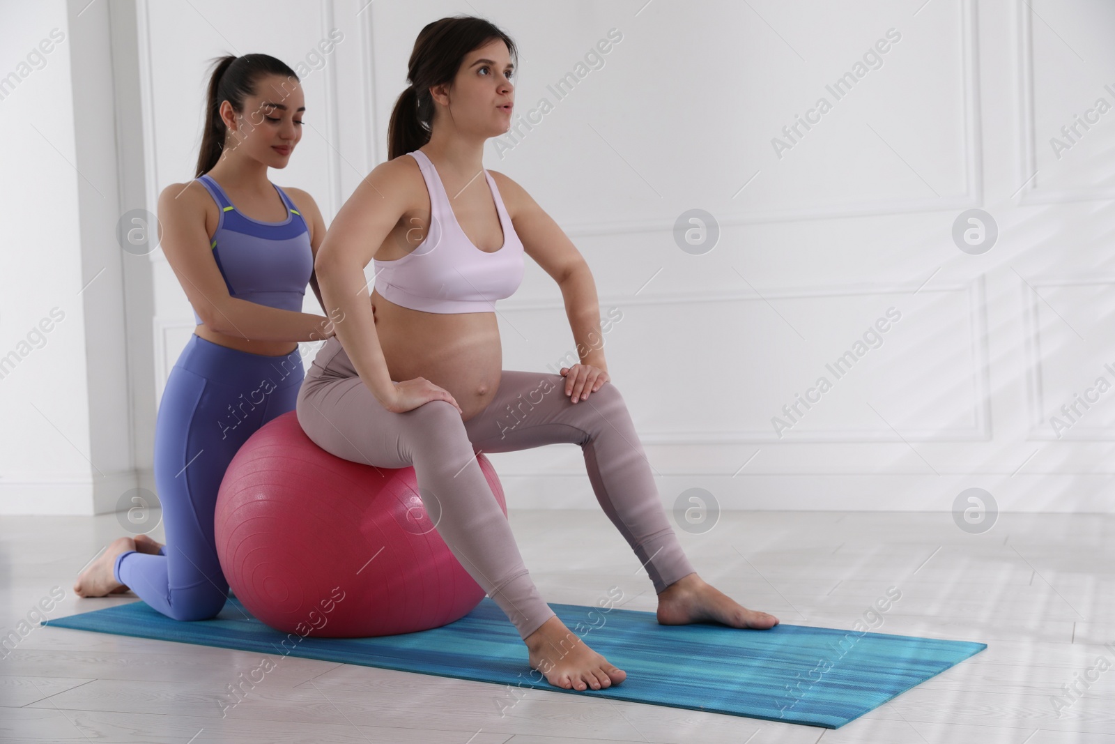 Photo of Trainer working with pregnant woman in gym. Preparation for child birth