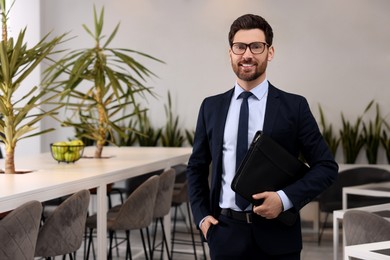 Happy real estate agent with leather portfolio in office