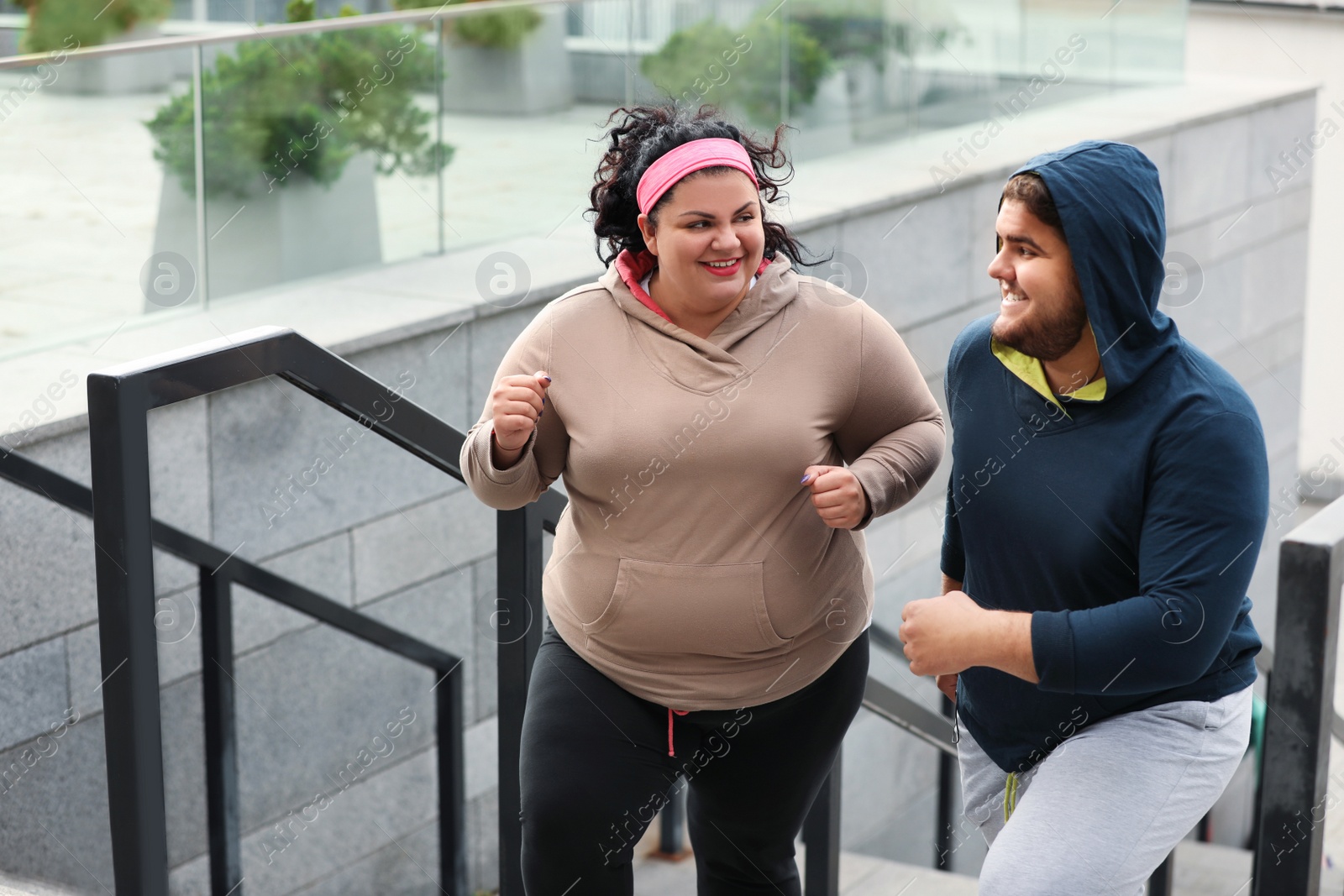 Photo of Overweight couple running up stairs together outdoors