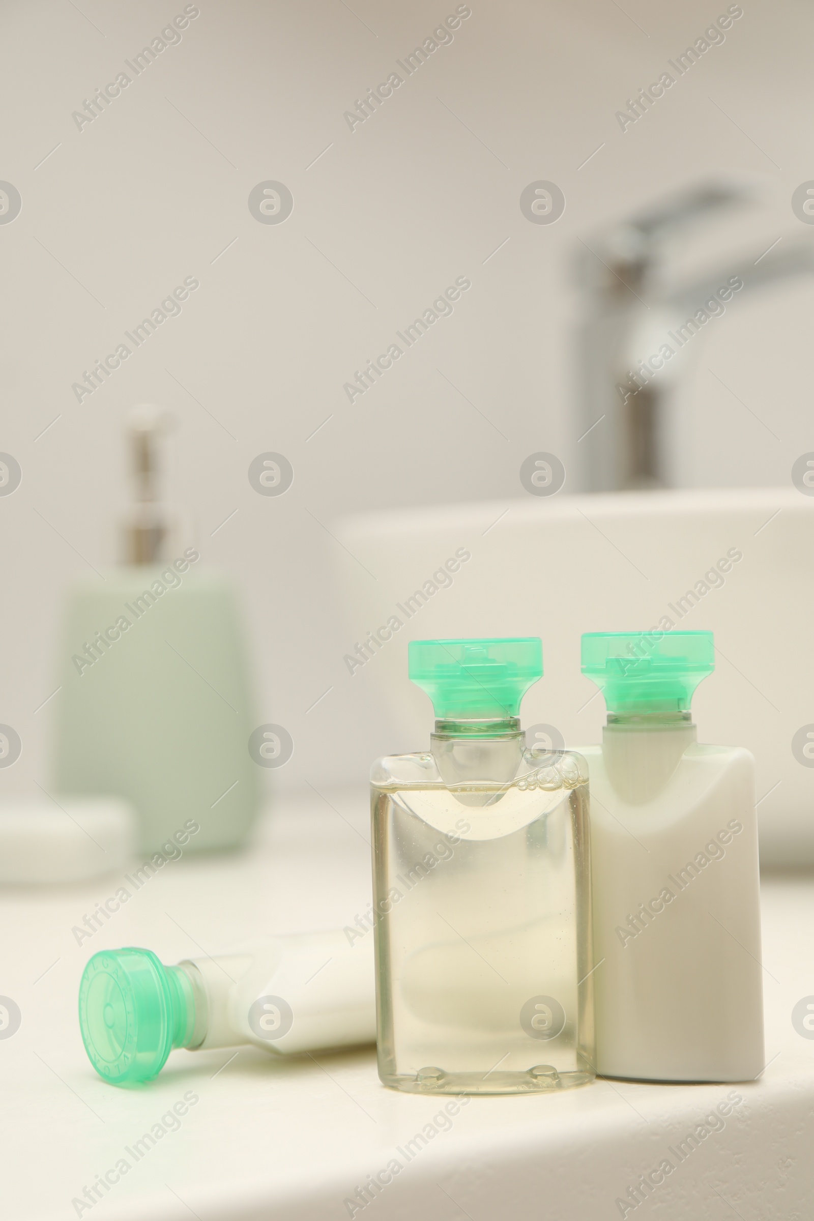 Photo of Mini bottles of cosmetic products on white countertop in bathroom