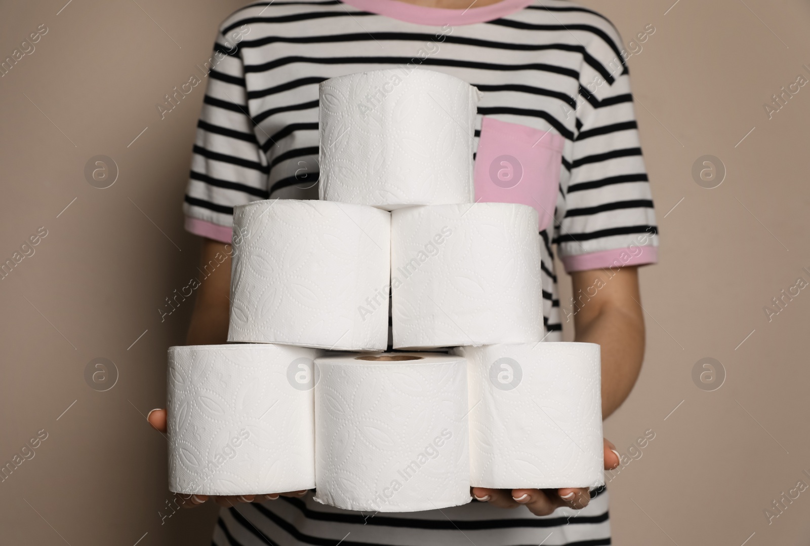 Photo of Woman with heap of toilet paper rolls on beige background, closeup