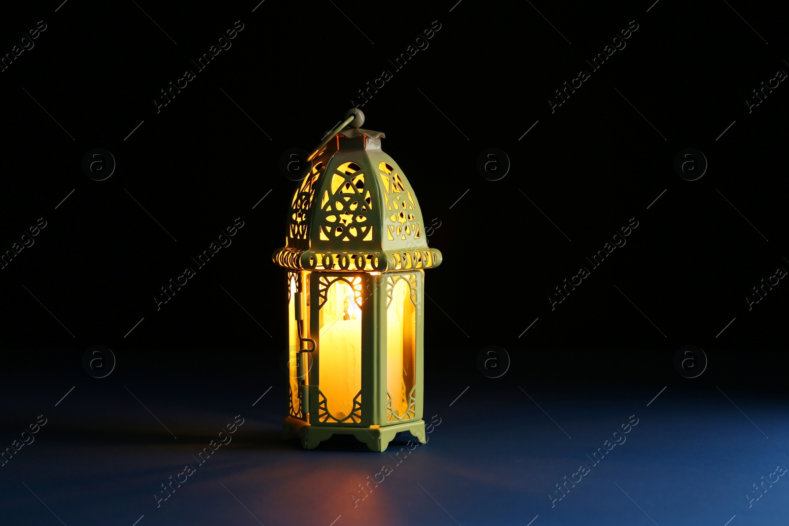 Photo of Decorative Arabic lantern on table against dark background. Space for text