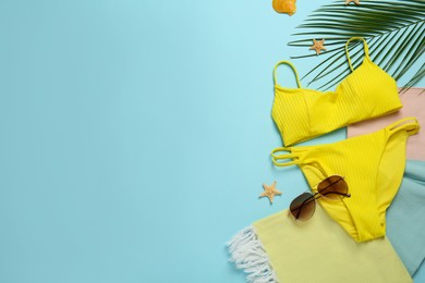 Photo of Beach towel, swimsuit and sunglasses on light blue background, flat lay. Space for text