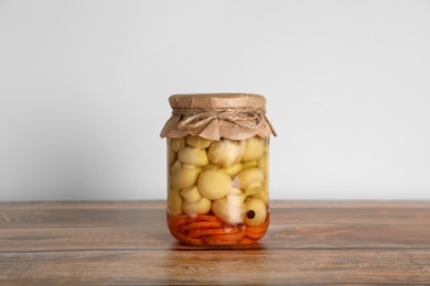 Photo of Jar with pickled mushrooms and carrots on wooden table