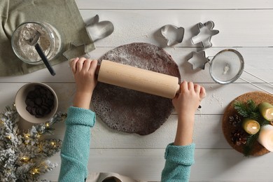 Photo of Little child rolling dough for Christmas cookies at white wooden table, top view