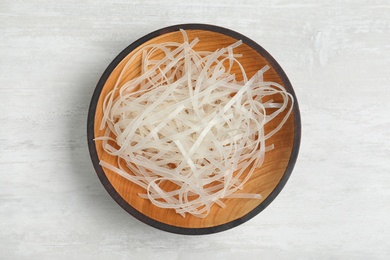 Plate of uncooked rice noodles on light table, top view