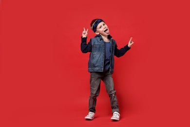 Photo of Happy little boy dancing on red background