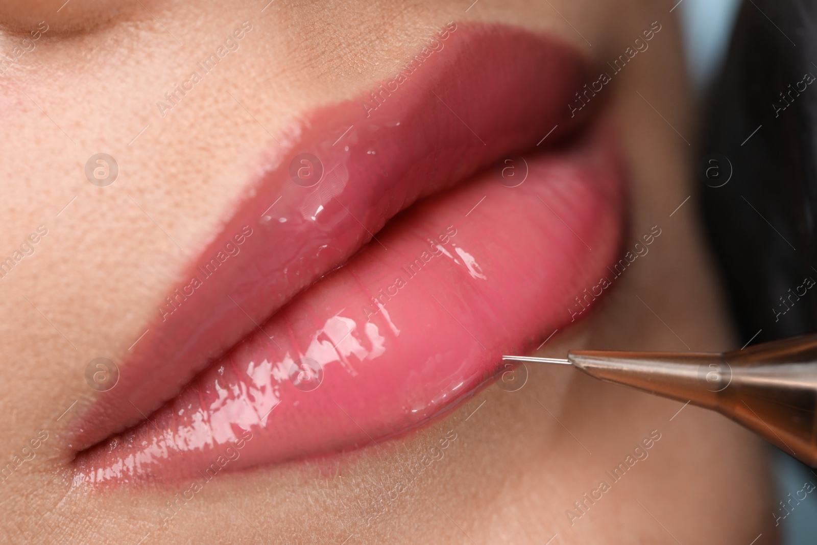 Photo of Young woman during procedure of permanent lip makeup in beauty salon, closeup