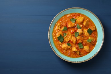 Photo of Delicious chicken curry on blue wooden table, top view. Space for text