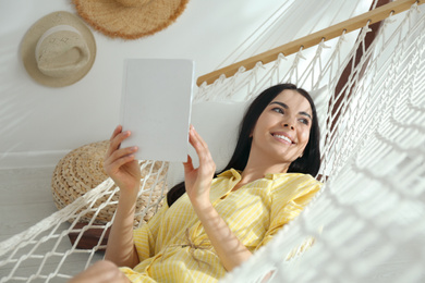 Young woman reading book in hammock at home