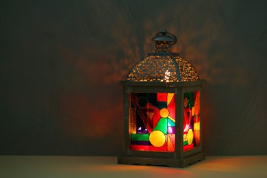 Photo of Decorative Arabic lantern on table against dark background. Space for text