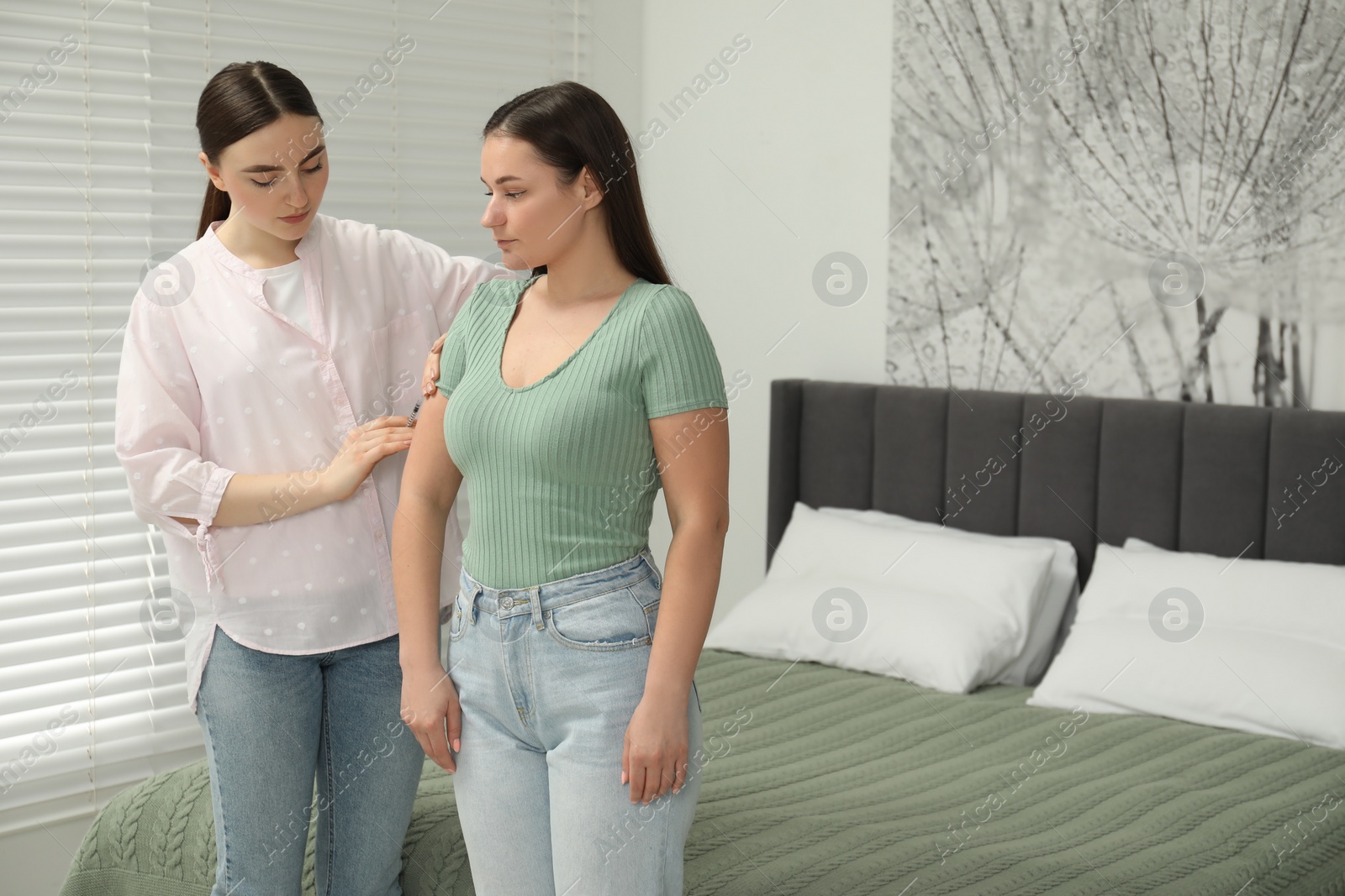 Photo of Woman giving insulin injection to her diabetic friend in bedroom