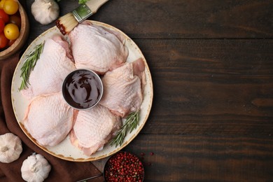 Photo of Flat lay composition with fresh marinade, raw chicken, rosemary and other products on wooden table. Space for text