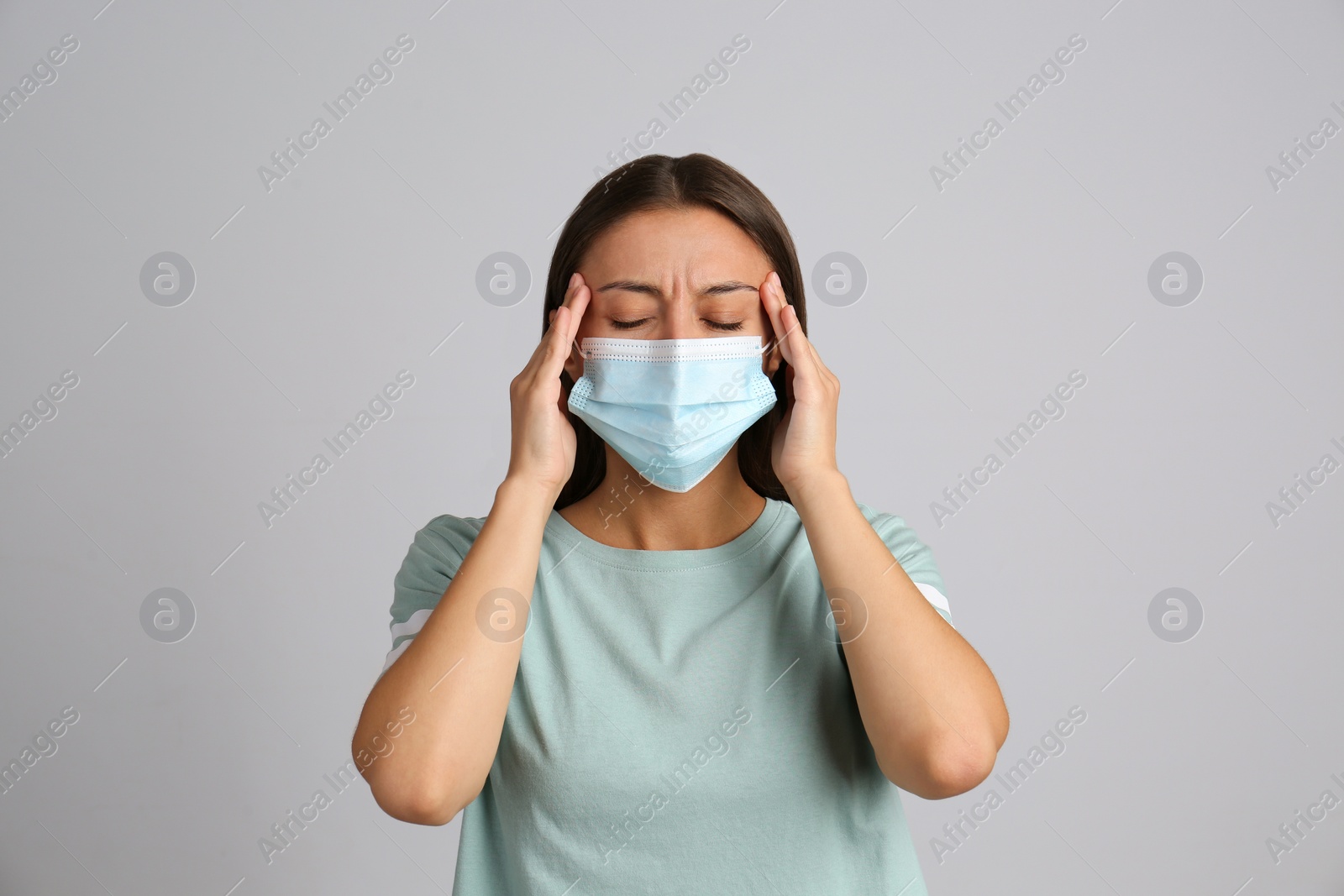 Photo of Stressed woman in protective mask on grey background. Mental health problems during COVID-19 pandemic