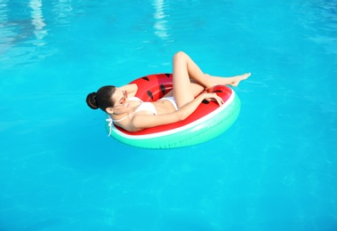 Photo of Beautiful young woman wearing bikini on inflatable ring in swimming pool