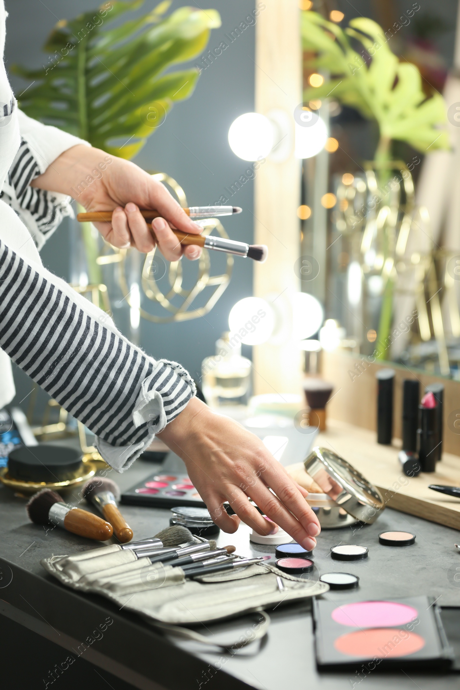 Photo of Professional makeup artist near dressing table with decorative cosmetics in beauty salon