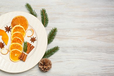 Photo of Flat lay composition with dry orange slices, anise stars, cinnamon sticks and fir branches on white wooden table, flat lay. Space for text