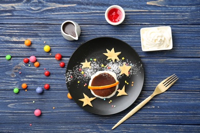 Photo of Flat lay composition with chocolate pancake and candies on wooden background. Creative breakfast ideas for kids