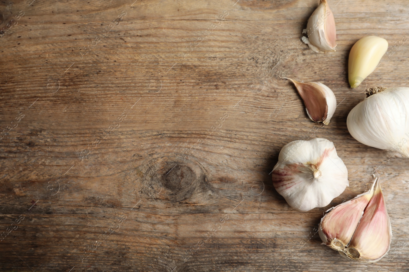 Photo of Fresh organic garlic on wooden table, flat lay. Space for text