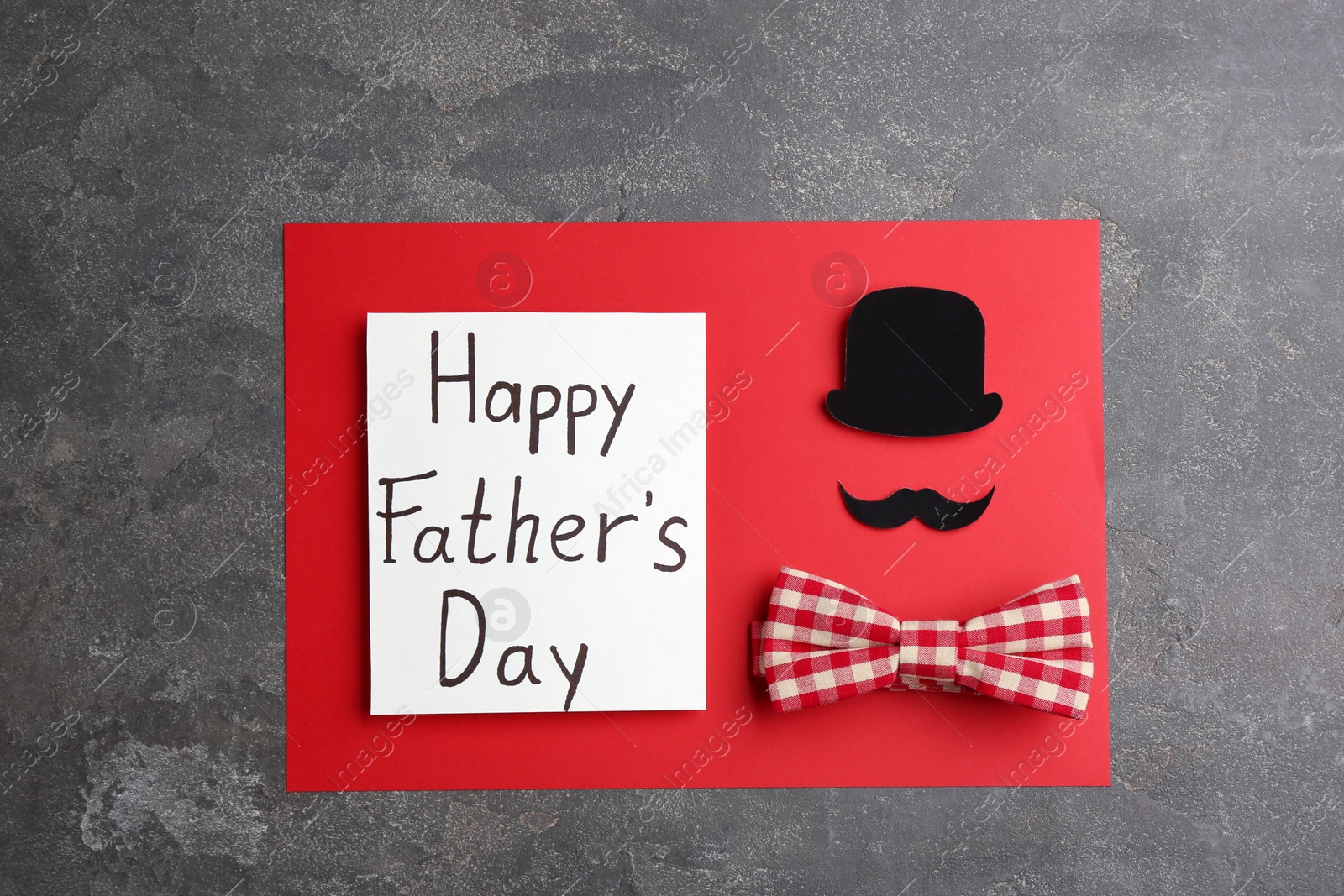 Photo of Greeting card with words HAPPY FATHER'S DAY on grey stone background, top view