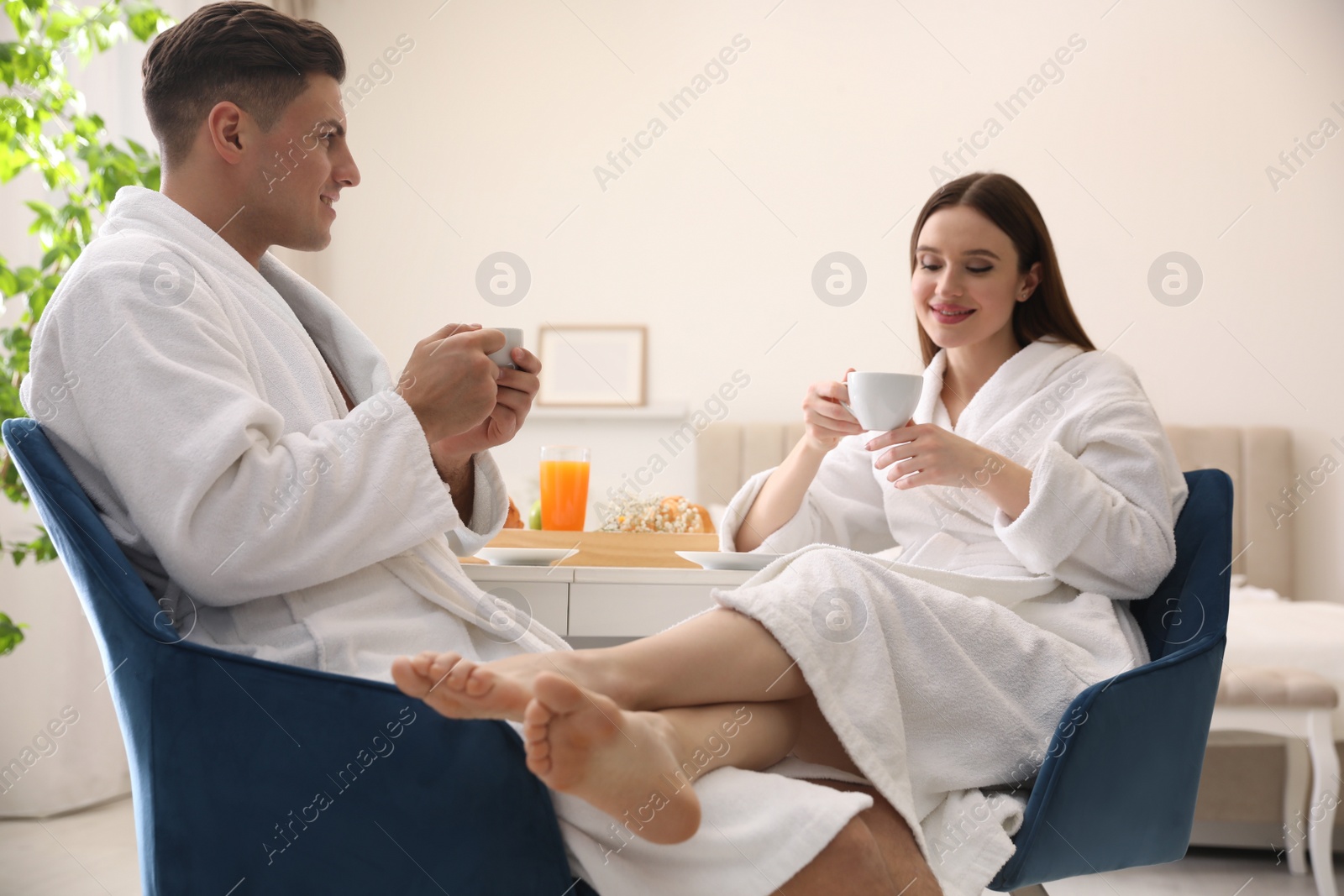 Photo of Happy couple in bathrobes having breakfast at home