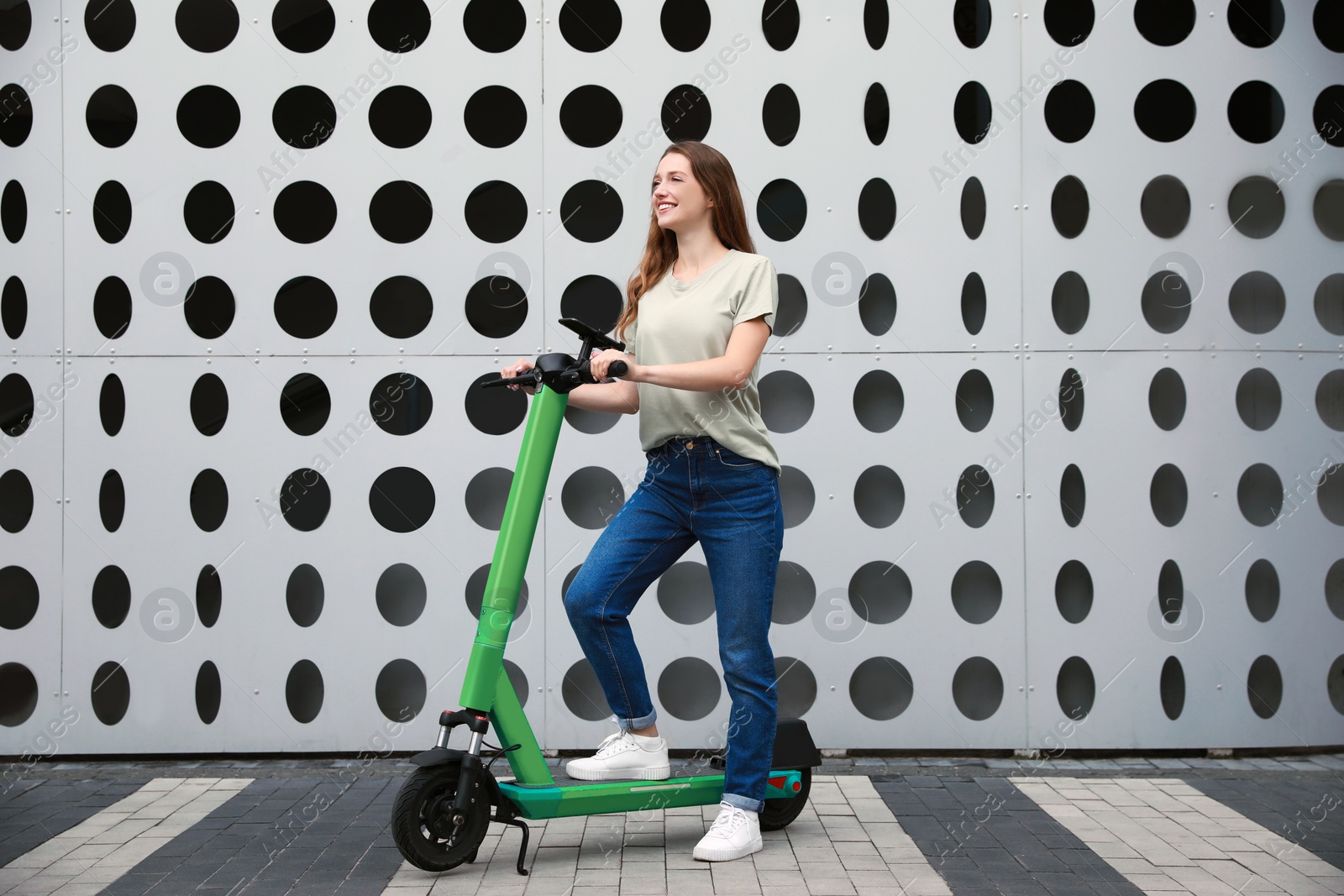 Photo of Happy woman with modern electric kick scooter on city street