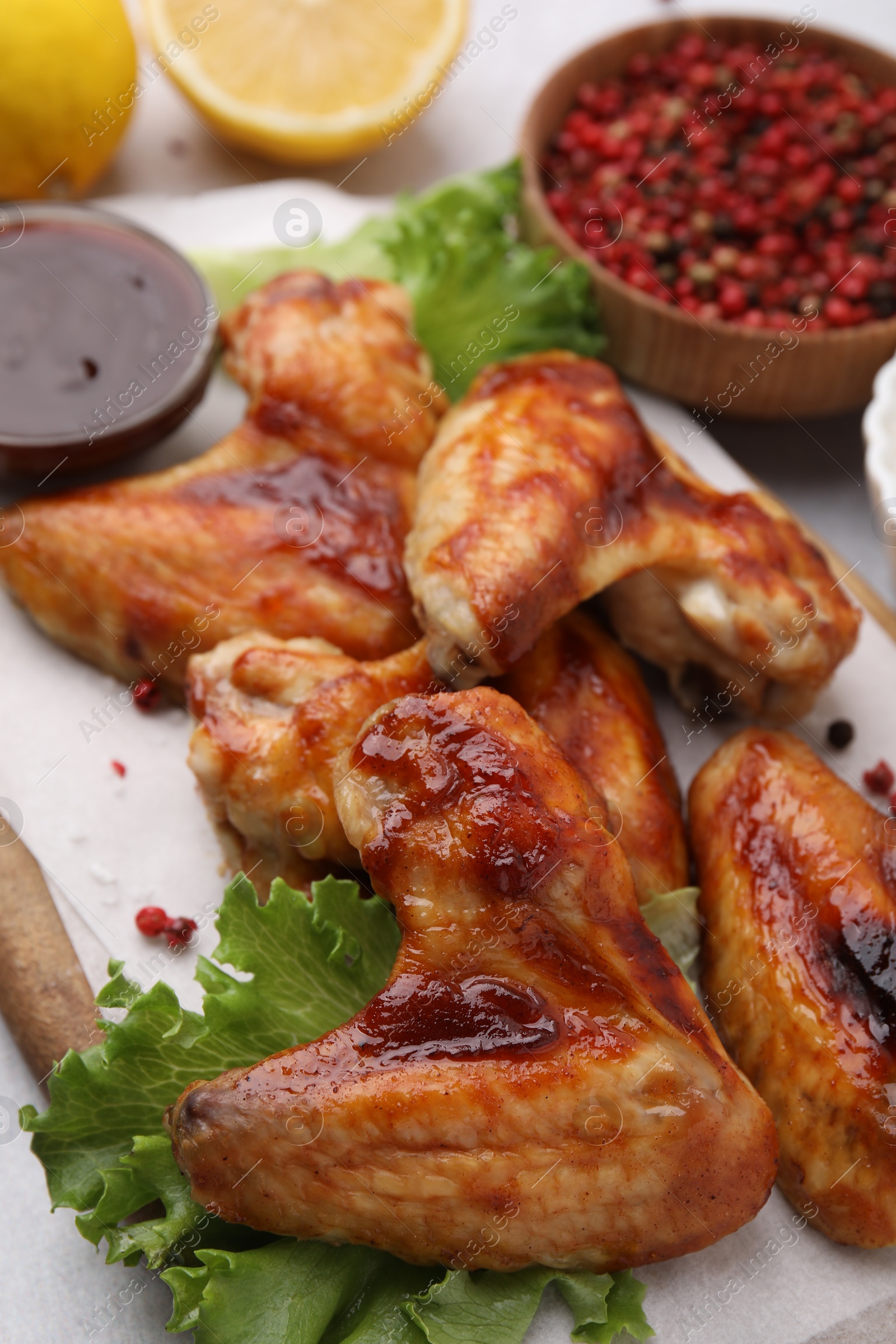 Photo of Fresh marinated chicken wings, spices and lettuce on light table, closeup