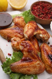 Photo of Fresh marinated chicken wings, spices and lettuce on light table, closeup