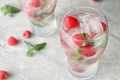 Glass of refreshing drink with raspberry and mint on grey stone table, closeup view. Space for text