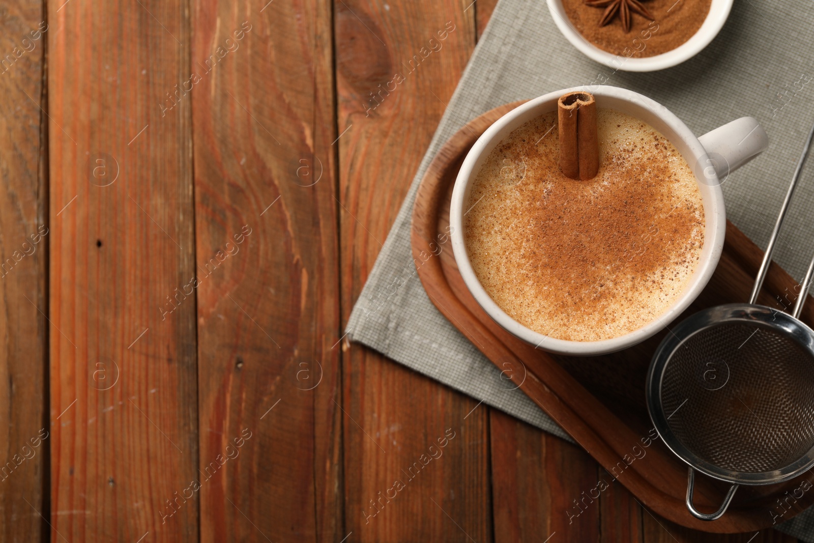 Photo of Delicious eggnog with anise and cinnamon on wooden table, top view. Space for text