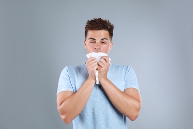 Photo of Young man suffering from allergy on grey background