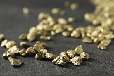 Photo of Shiny gold nuggets on grey textured surface, closeup