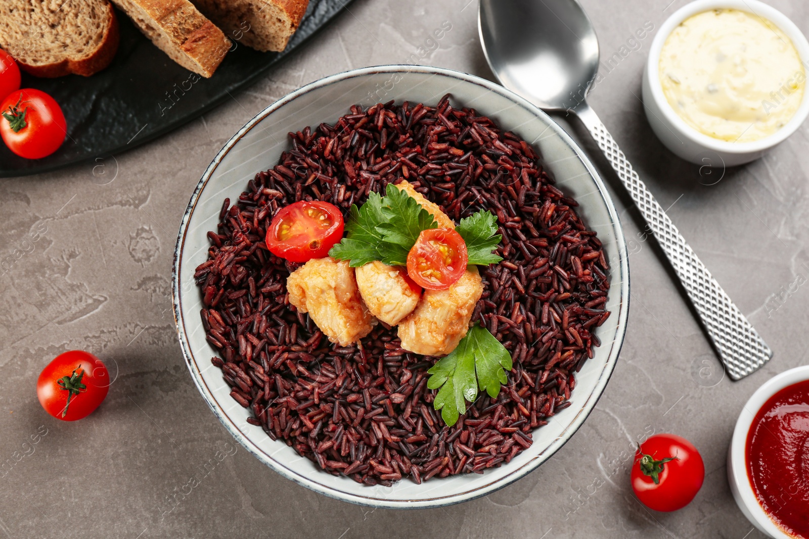 Photo of Tasty brown rice with chicken served on grey table, flat lay