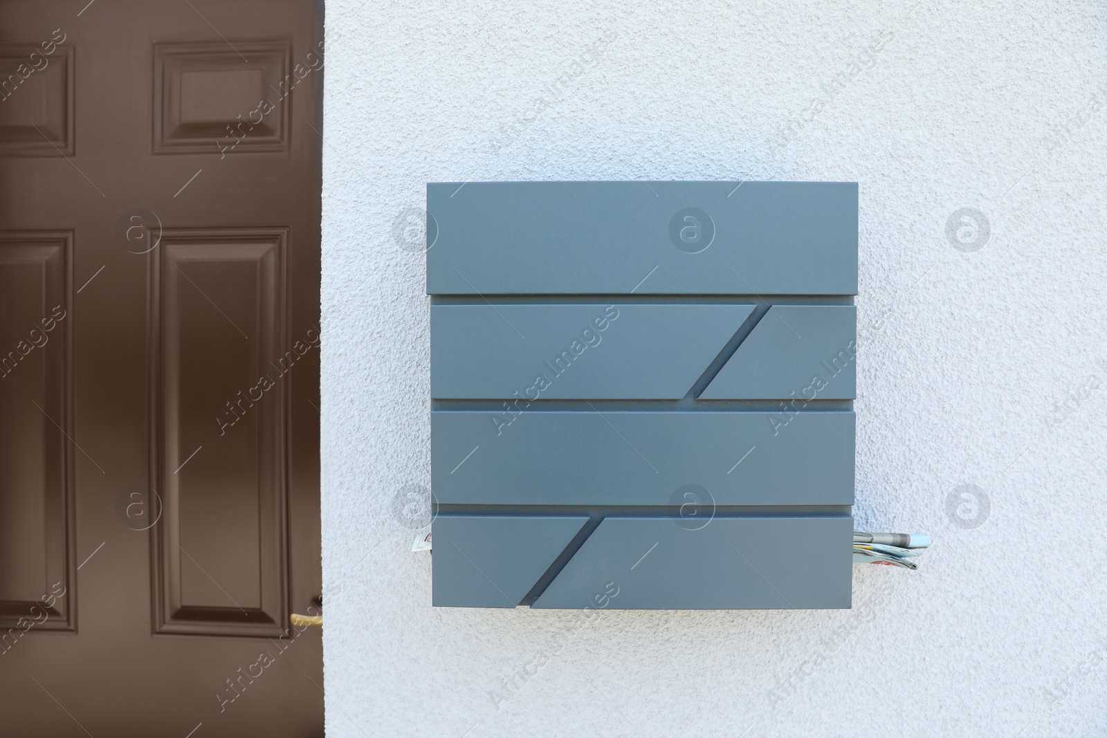 Photo of Grey metal letter box on white wall near entrance