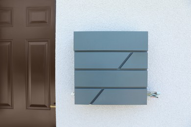 Photo of Grey metal letter box on white wall near entrance