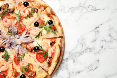 Photo of Tasty pizza with seafood on white marble table, top view. Space for text