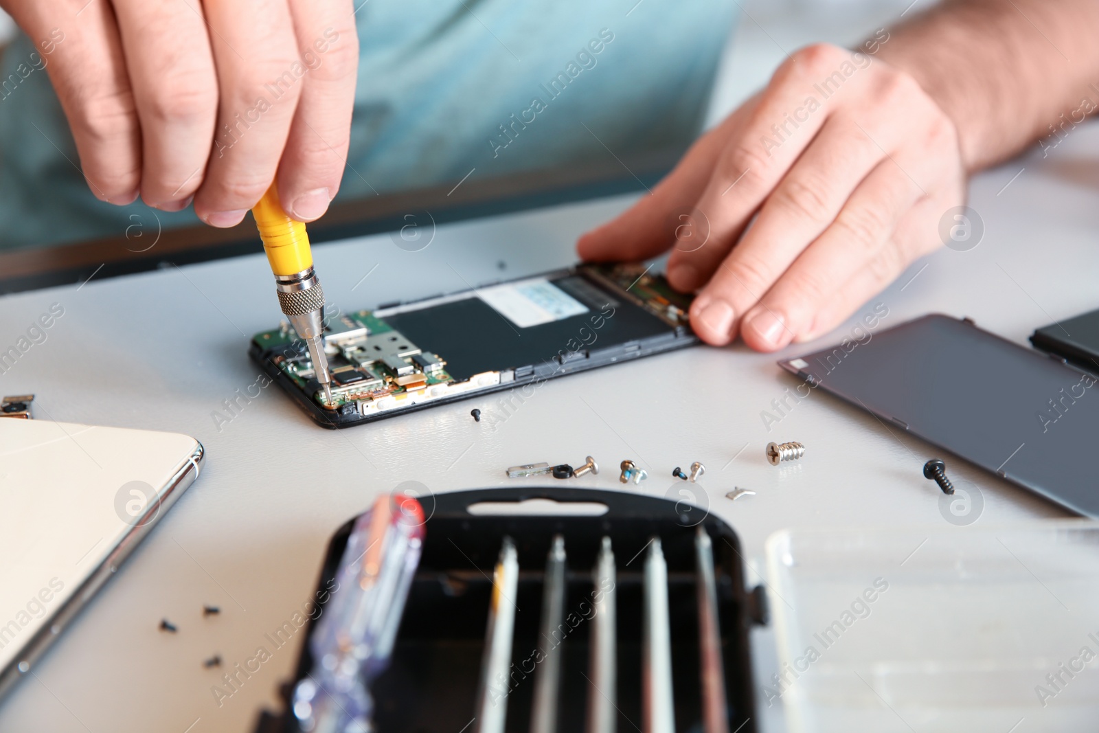 Photo of Technician repairing mobile phone at table, closeup