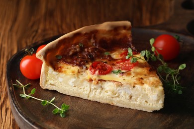 Piece of delicious homemade quiche with prosciutto, tomatoes and greens on serving board, closeup