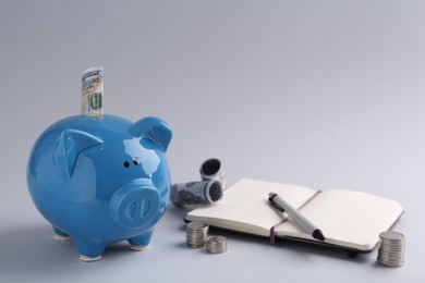 Photo of Financial savings. Piggy bank, dollar banknotes, coins and stationery on grey background