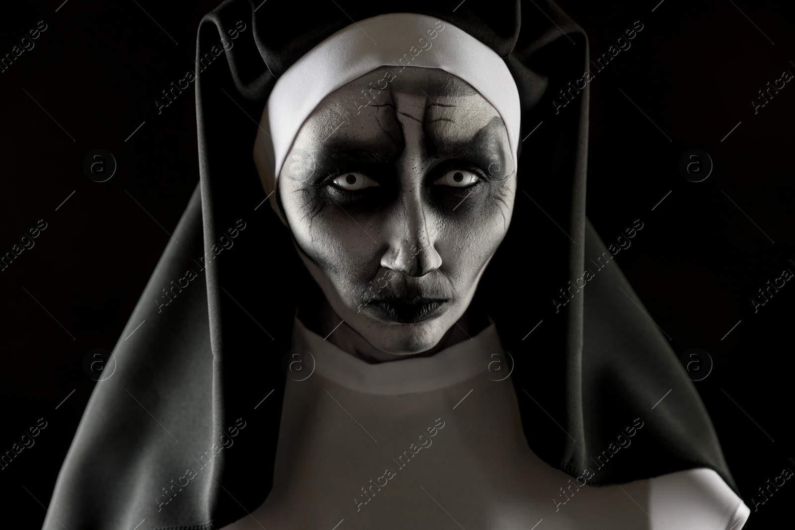 Photo of Portrait of scary devilish nun on black background. Halloween party look