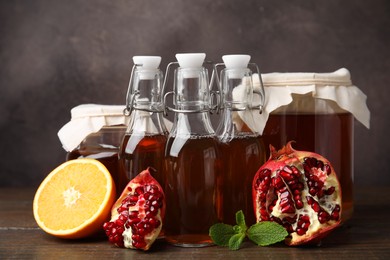 Photo of Tasty kombucha, mint and fresh fruits on wooden table