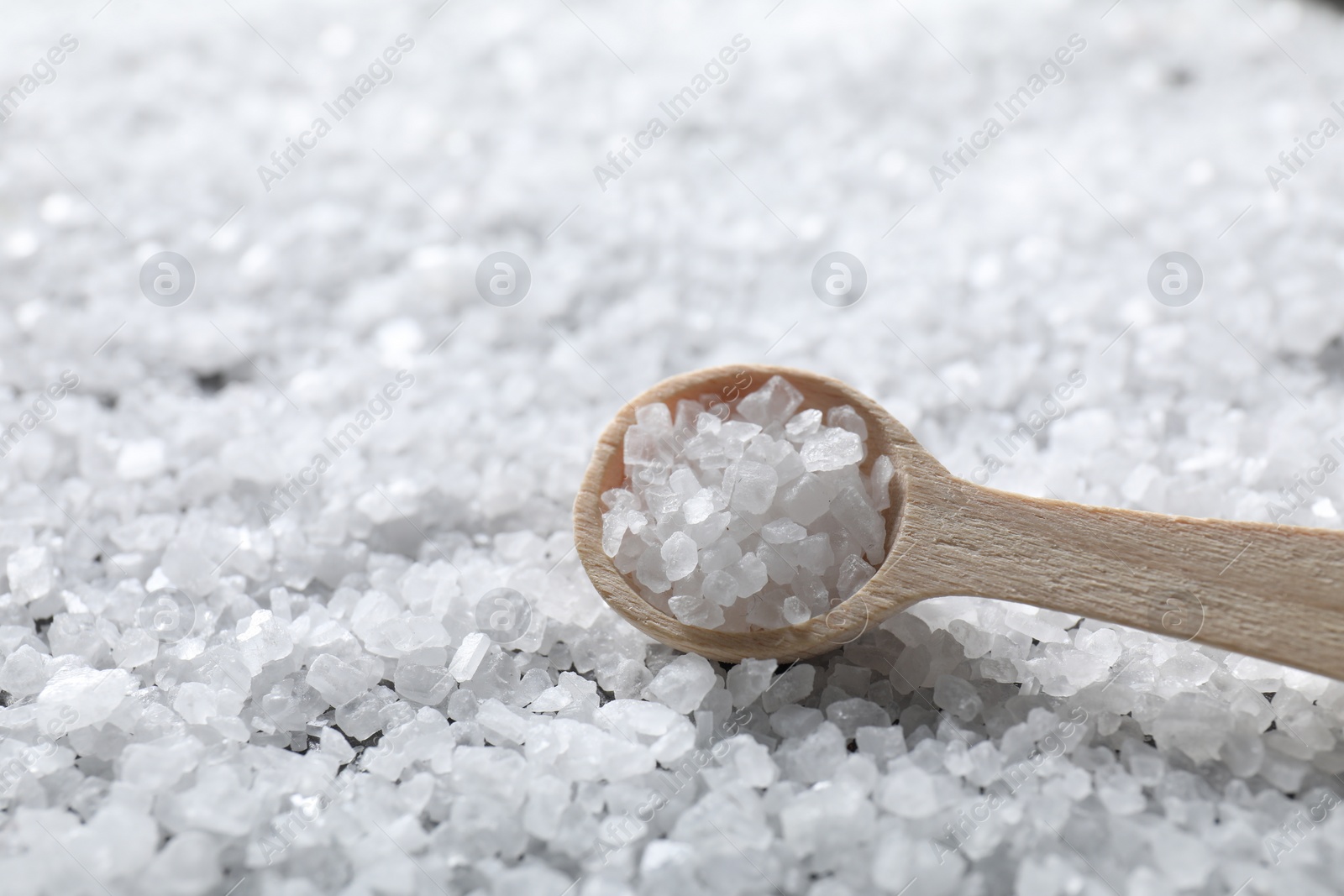 Photo of Natural salt and wooden spoon, closeup view