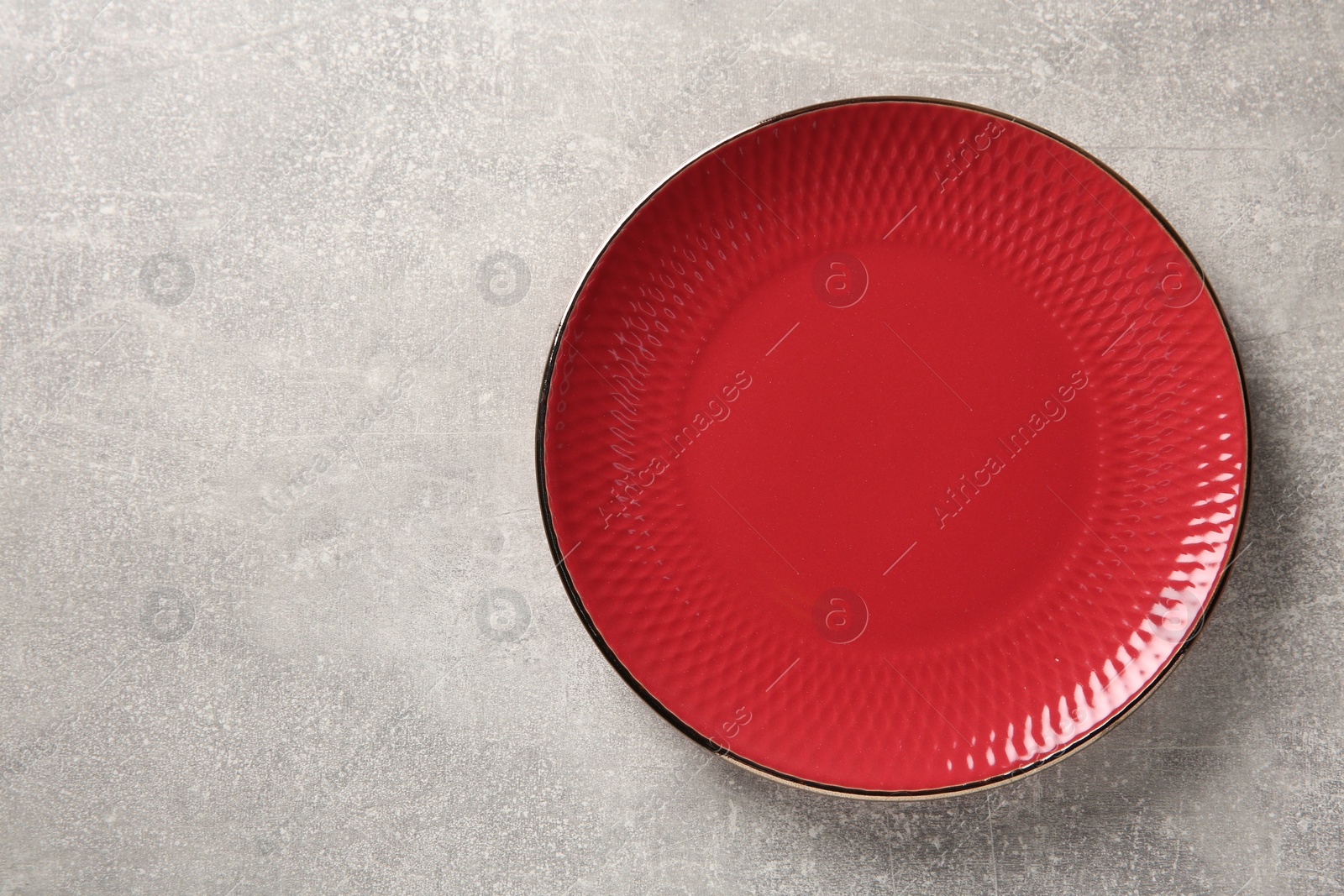 Photo of One red ceramic plate on light grey table, top view. Space for text