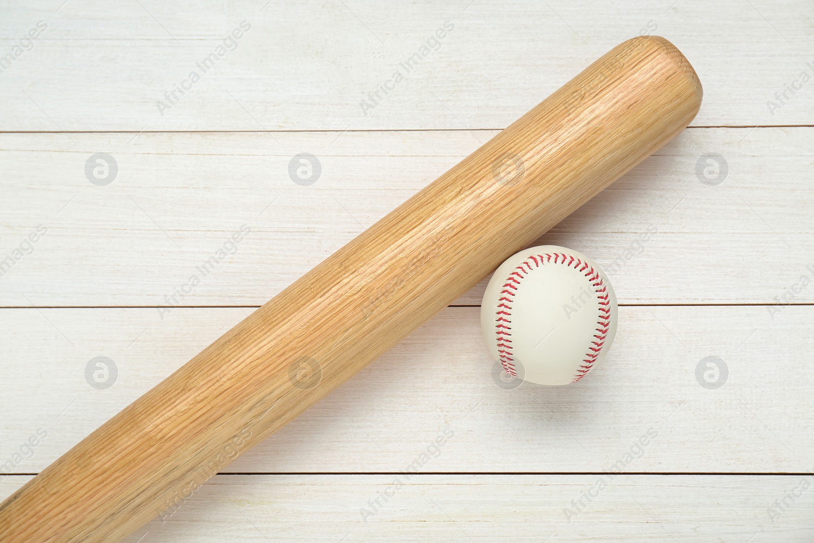 Photo of Baseball bat and ball on white wooden table, top view. Sports equipment