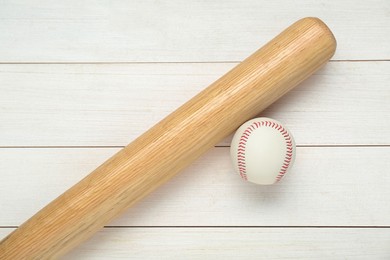 Photo of Baseball bat and ball on white wooden table, top view. Sports equipment