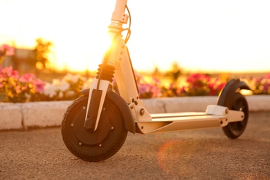 Modern electric kick scooter outdoors on sunny day, closeup