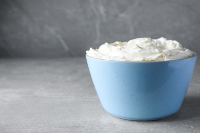 Photo of Bowl of tasty cream cheese on light grey table, space for text