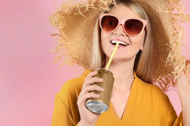 Beautiful happy woman drinking from beverage can on pink background